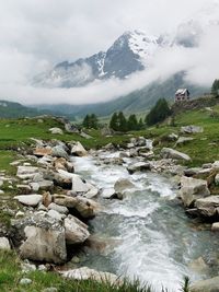 Stream flowing through rocks against sky