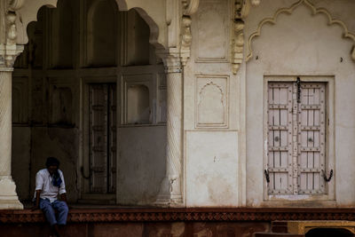 Rear view of man sitting at old building