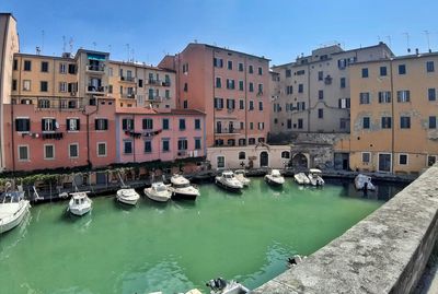 Boats moored in canal amidst buildings in city against sky