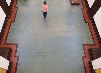 Rear view of woman walking on tiled floor