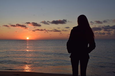 Silhouette man looking at sea against sky during sunset