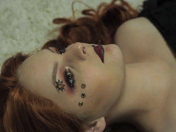 Teenage girl with decorations on face looking away while lying down