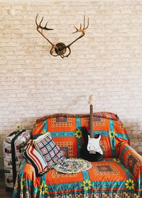 Guitar on a sofa against a white brick wall 