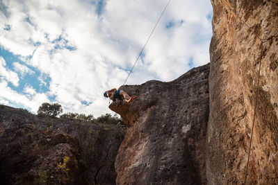 Low angle view of person on rock against sky