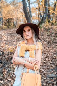 Portrait of smiling woman standing by tree during autumn