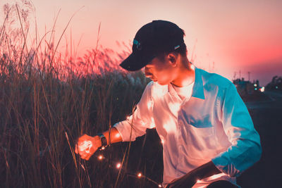 Young man standing on field against sky during sunset