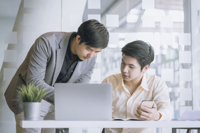 Male colleagues discussing at desk in office