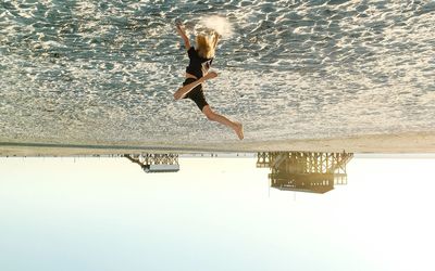 Woman jumping in swimming pool against sea