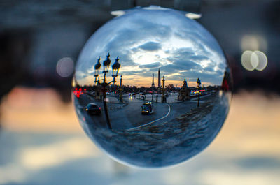 Digital composite image of crystal ball and cityscape against sky