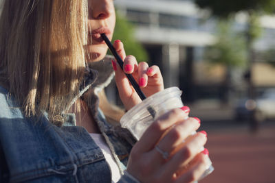 Midsection of woman drinking coffee in city