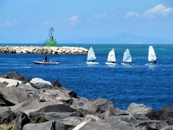 Boats sailing in sea against sky