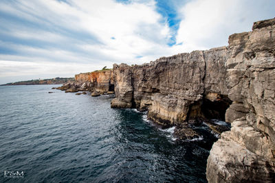 Rock formations by sea against sky