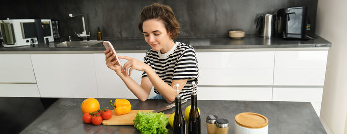 Side view of young woman using mobile phone at home