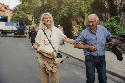 Cheerful senior couple strolling on street in city