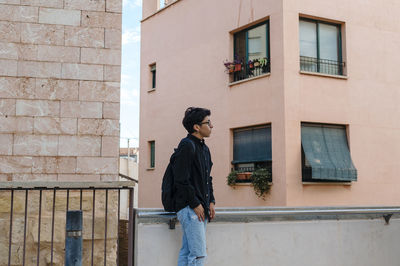 Young transgender man posing outdoors in the narrow street of a town.