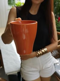 Midsection of woman holding brown mug 