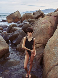 Portrait of young woman sitting on rock at beach
