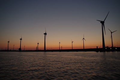 Silhouette cranes against sky during sunset