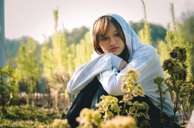 Portrait of young woman sitting on the field, she looks so sad, maybe she need someone to talk