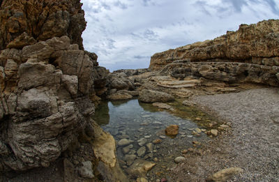 Rock formation on shore against sky