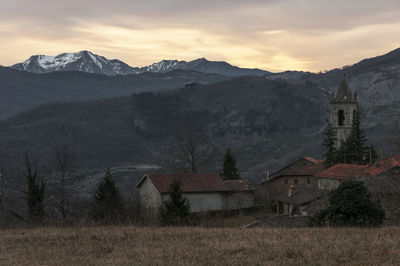 Houses by mountains against sky during sunset