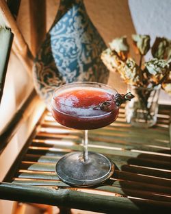 Close-up of red drink in cocktail glass on wooden bamboo table