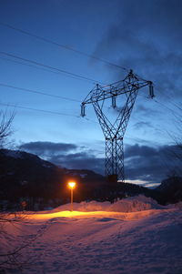 Electricity pylons on field against sky during winter