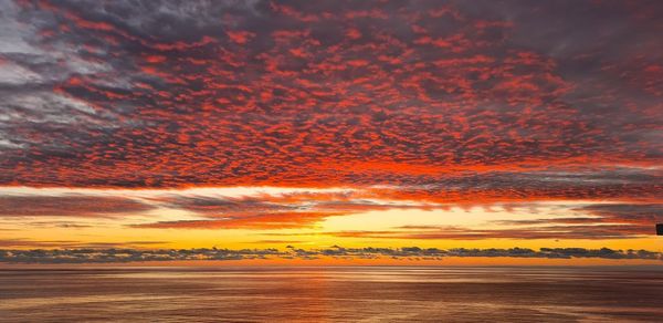 Scenic view of sea against dramatic sky during sunset