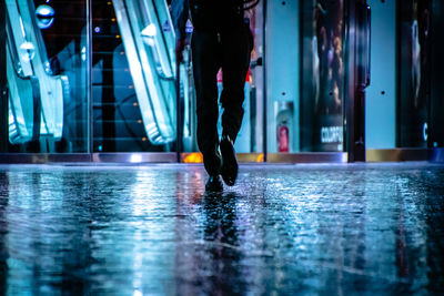 Low section of man walking on illuminated street at night