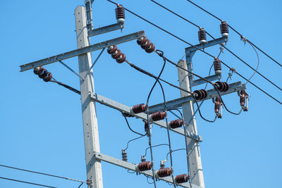 Low angle view of electricity transformer against clear blue sky