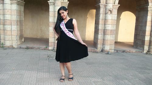 Full length portrait of bridesmaid standing against building