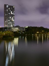 Illuminated buildings by city against sky at night