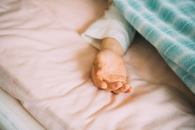 Cropped hand of child on bed