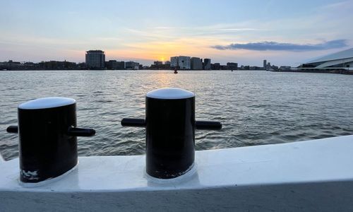 Scenic view of sea by buildings against sky during sunset