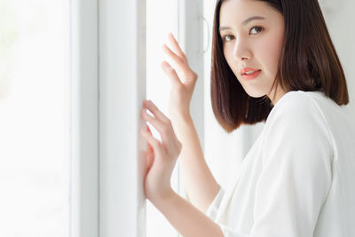 Portrait of woman standing by window