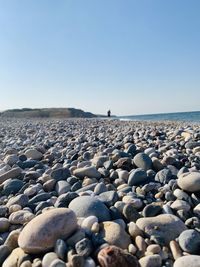 View of pebbles on beach against clear sky