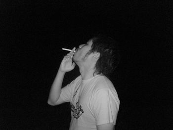 Man smoking cigarette against black background