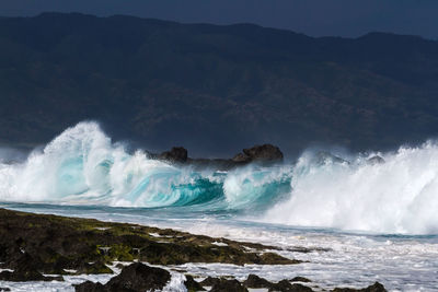 Scenic view of waves in sea against sky