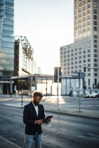 Businessman in smart casual using digital tablet on street