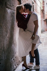 Side view of young couple kissing against wall