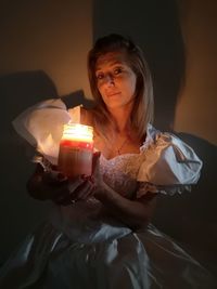 Portrait of woman holding lit candle