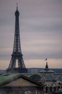 Communications tower in city against sky