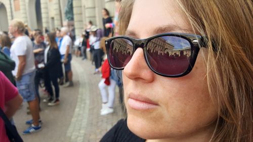 Close-up of woman wearing sunglasses with crowd in city