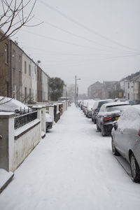 Snow covered road amidst buildings in city