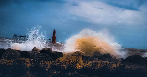 People on rock by sea against sky