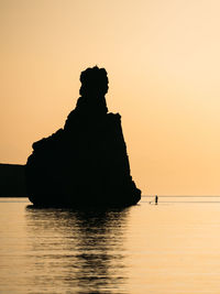 Silhouette of a man floating on a supboard at sunset in ibiza