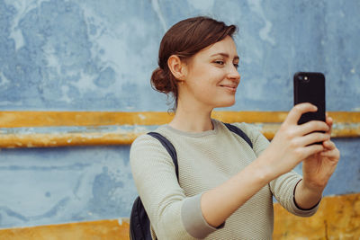 Young woman blogger taking selfies or photos with modern smartphone