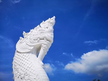 Low angle view of naga statue against blue sky