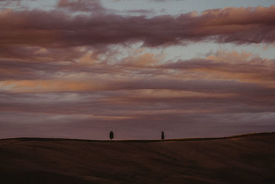 People on field against sky at sunset