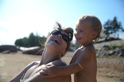 Happy woman and boy on beach against sky